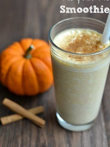 a glass of pumpkin smoothie with a small pumpkin