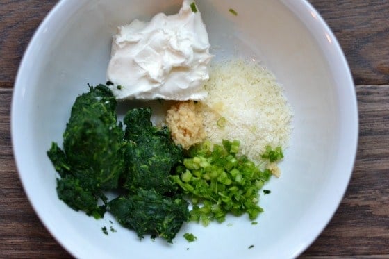 Spinach, cream cheese, garlic and scallions in a white bowl