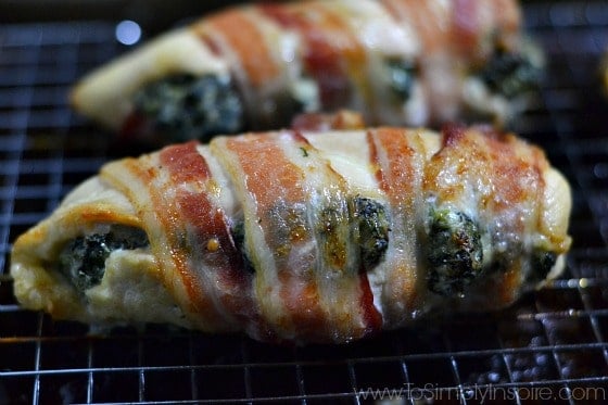 closeup of 2 Spinach Cream Cheese Stuffed Chicken Breasts wrapped in Bacon on a wire rack
