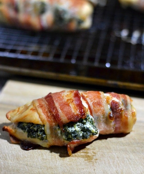 Scrumptious Spinach Cream Cheese Stuffed Chicken Breasts wrapped in Bacon! Perfect easy dish for your family and guests. Spinach Stuffed Chicken Breasts wrapped in Bacon on a wood cutting board