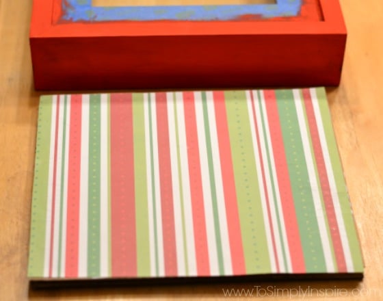 a red green and white striped piece of paper on a table beside a red wooded shadowbox frame