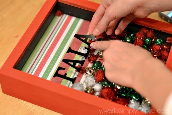black vinyl letters being placed on the glass of a shadowbox frame