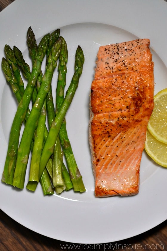 Pan Cooked Salmon on white plate with asparagus spears and lemon slices