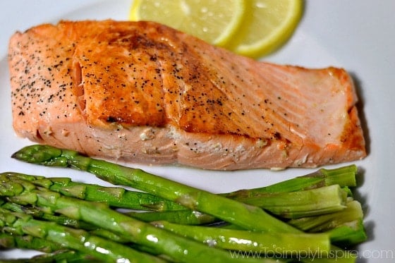 Pan Seared Salmon on a white plate with asparagus and 2 slices of lemon