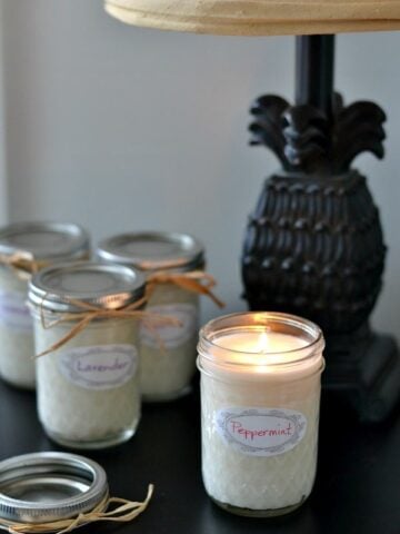 mason jar candle lit with 3 candles in the background