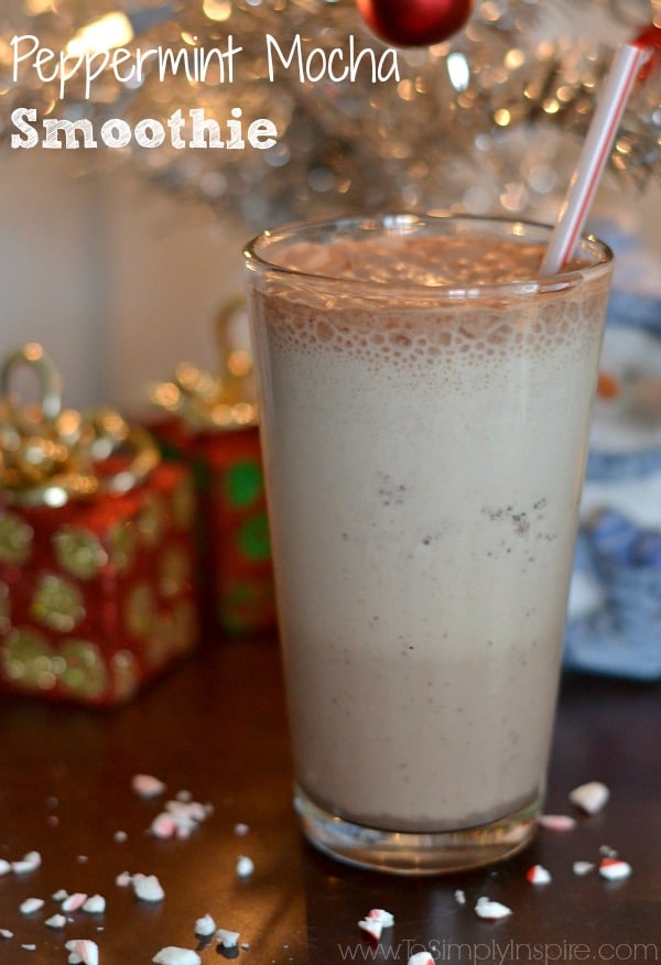 a glass of peppermint mocha smoothie with a straw with christmas lights in the background