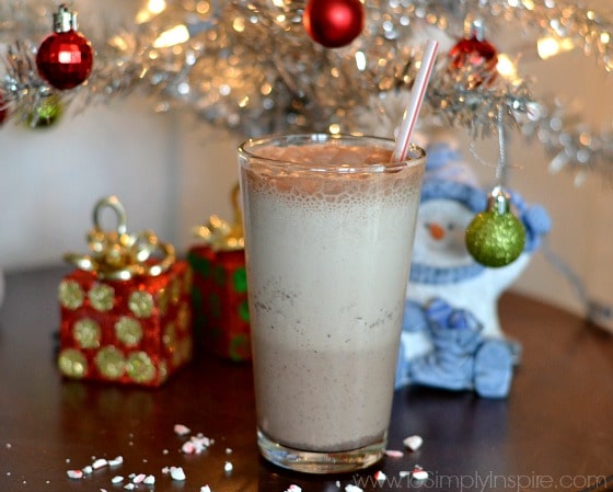 a glass of peppermint mocha smoothie with a straw with a silver christmas tree in the background