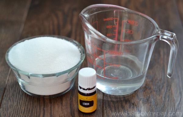 a glass measuring cup, a small glass bowl of sugar and lemon essential oil