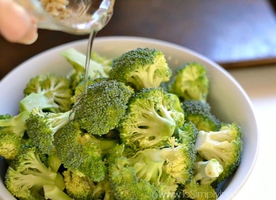 pouring oil over uncooked broccoli
