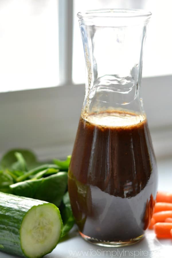 a bottle of homemade balsamic vinaigrette surrounded by fresh vegetables 