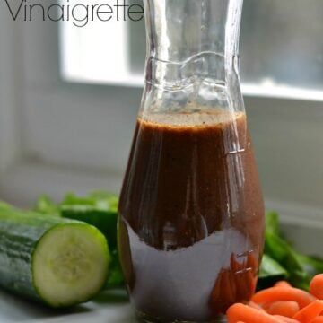 a bottle of homemade balsamic vinaigrette surrounded by fresh vegetables