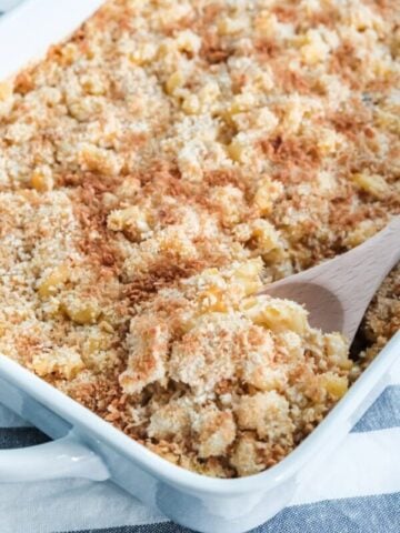 chicken casserole being scooped out of a white baking dish