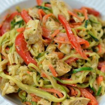 A plate of zucchini noodles, chicken and sliced red peppers