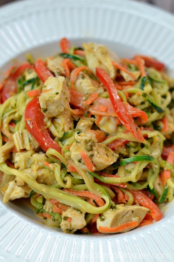 A closeup of zucchini noodles, chicken and sliced red peppers