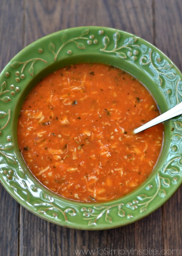 A green bowl of chicken tomato soup with a spoon