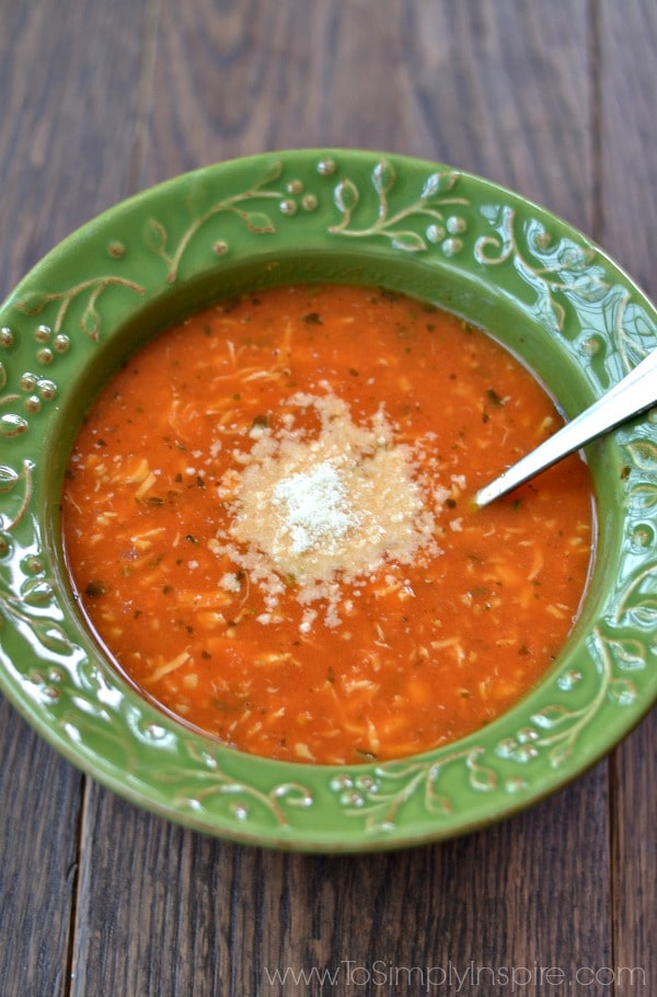 A green bowl of chicken tomato soup topped with parmesan cheese