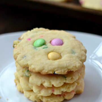 a stack of four cookies with pink, green and yellow m&m's