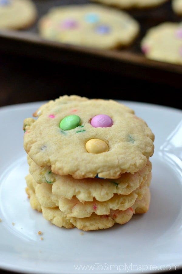 a stack of four cookies with pink, green and yellow m&m\'s