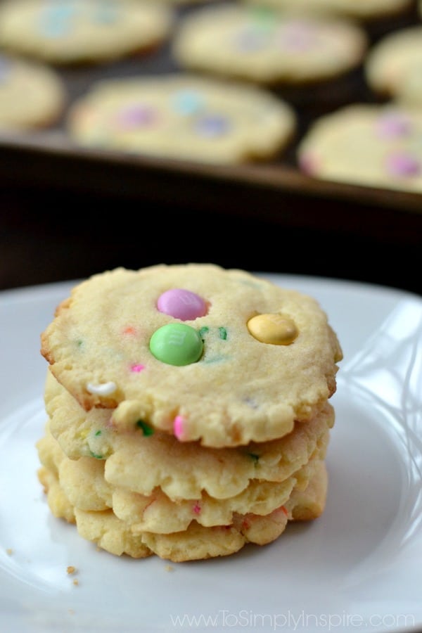 a stack of four cookies with pink, green and yellow m&m\'s