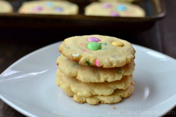 a stack of four cookies with pink, green and yellow m&m\'s