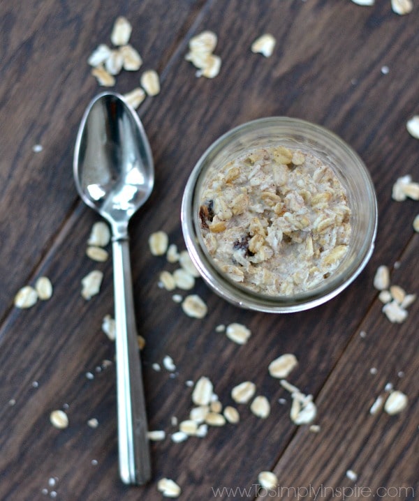a mason jar with oatmeal and a spoon lying beside it on a wood table