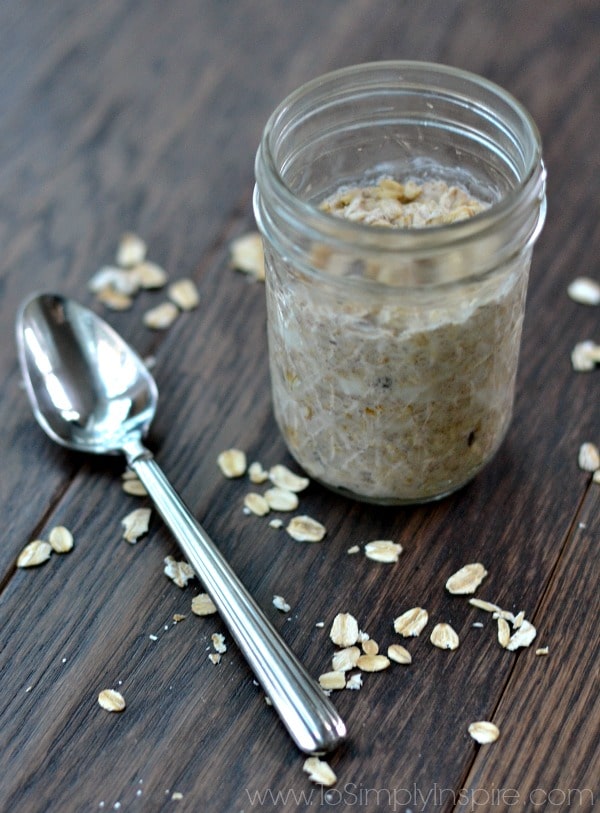 a mason jar with oatmeal and a spoon lying beside it on a wood table