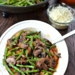 mushrooms and asparagus over cooked spaghetti squash in a white bowl