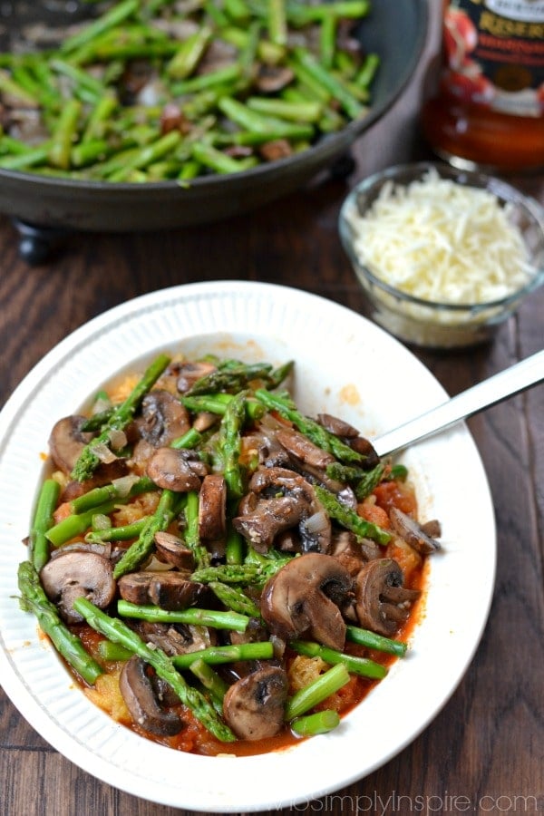 mushrooms and asparagus over cooked spaghetti squash in a white bowl