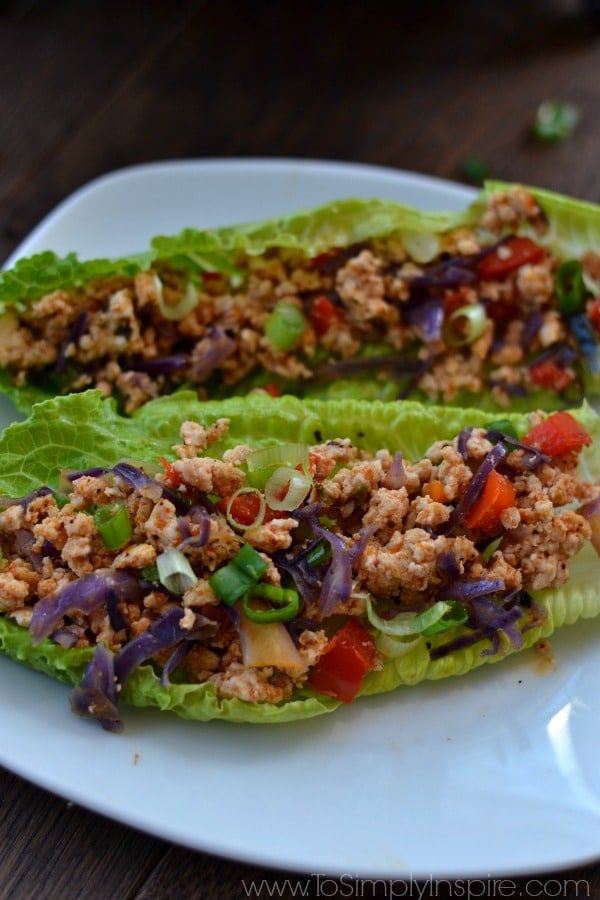 A closeup of a plate of two lettuce wraps with ground turkey meat and red peppers
