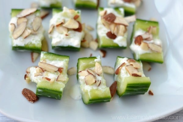 a plate full of cucumber slices topped with feta and almond slices 