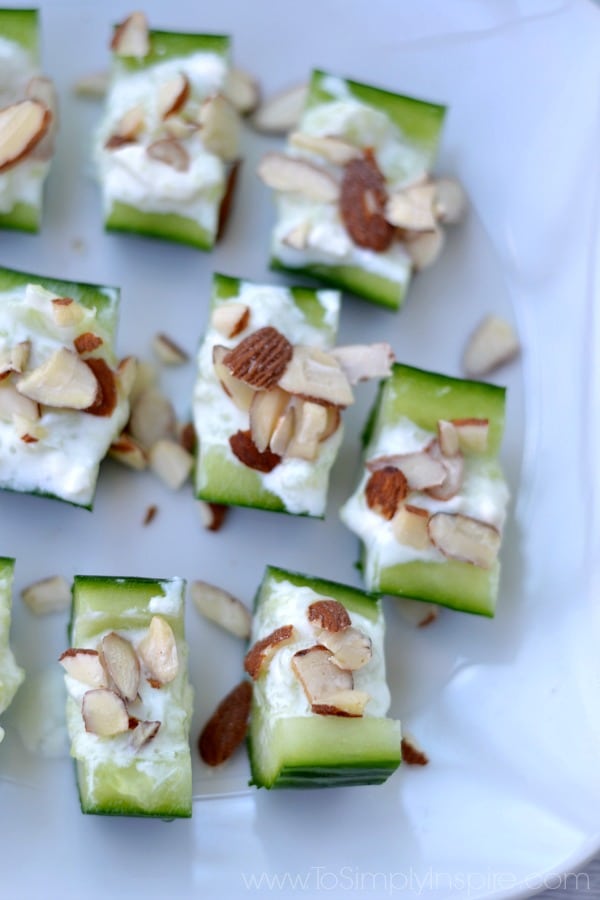 cucumber slices with feta and almond slices with a plate full in the back