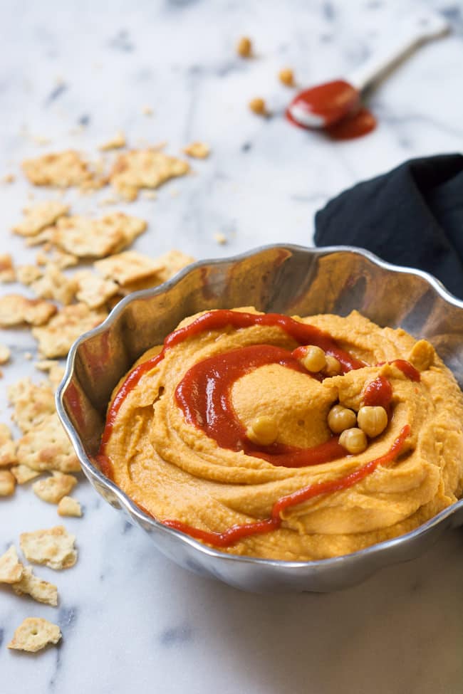 A silver bowl full of Siracha hummus