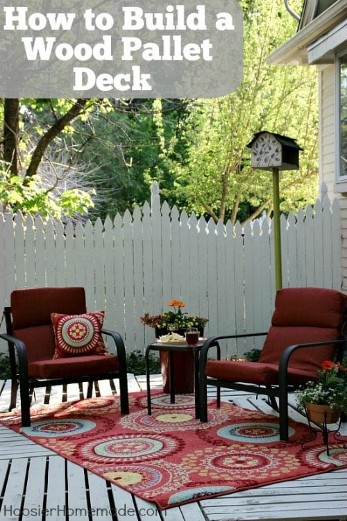 two chairs with red cushions in front of a white wood fence 