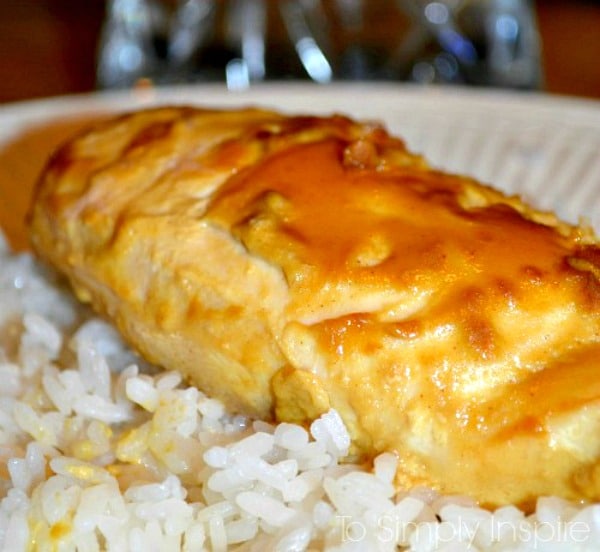 A close up of a chicken breast topped with maple dijon sauce over white rice