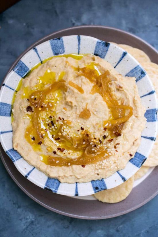 A blue and white plate hummus with oil on top