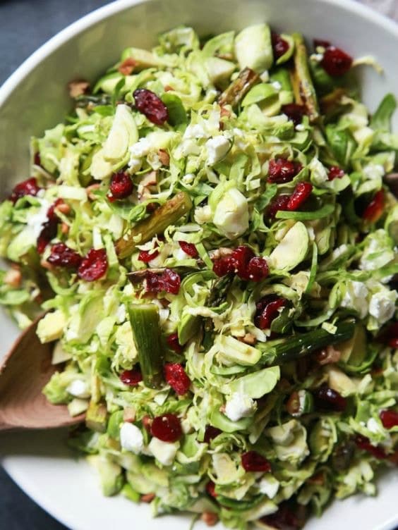 A bowl of salad with cranberries and asparagus