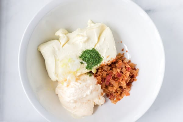 white bowl with cream cheese, bacon crumbles, mayo, and dill