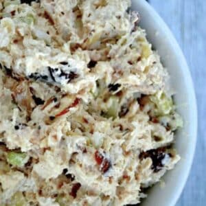 a white bowl full of chicken salad with cranberries