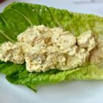 A plate of food with a piece of romaine lettuce filled with Curry chicken salad