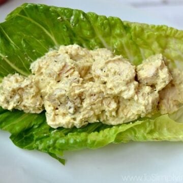 A plate of food with a piece of romaine lettuce filled with Curry chicken salad