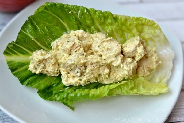 A white plate with a big piece of romaine lettuce with Curry chicken salad