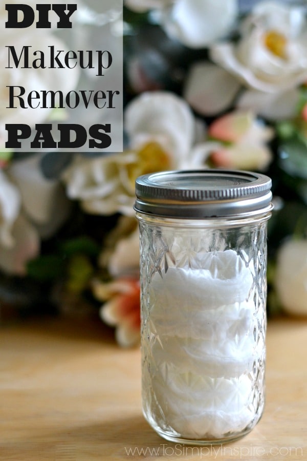 A close up of a mason jar of cotton rounds with flowers in the ivory flowers in the background