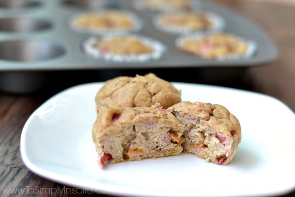 two banana rhubarb muffins on a white plate with one but in half 