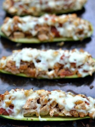 three chicken stuffed zucchini boats on a baking sheet