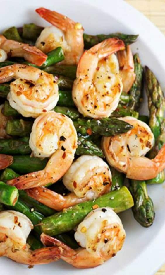 A plate of shrimp and asparagus in a lemon sauce