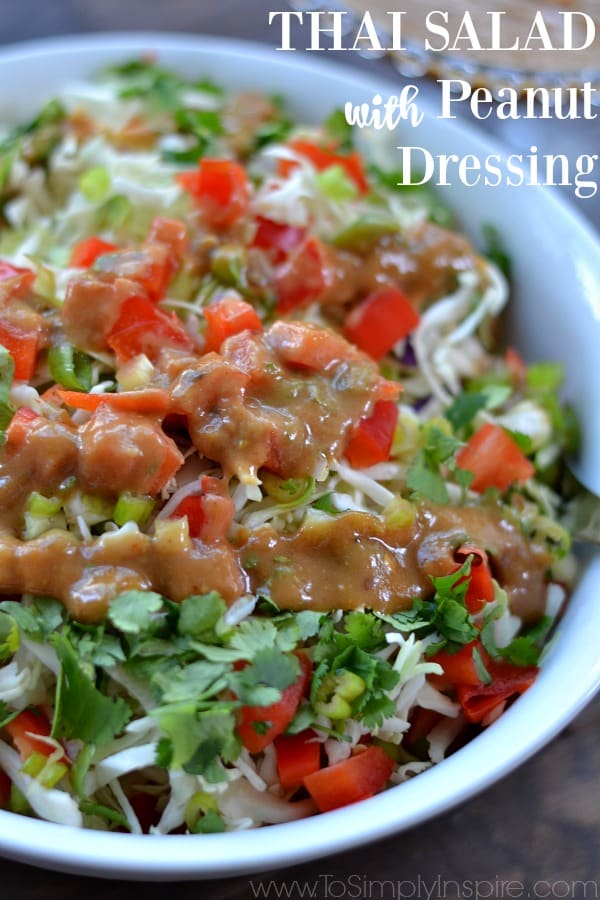 A close up of a bowl of salad with red peppers and topped with Thai dressing