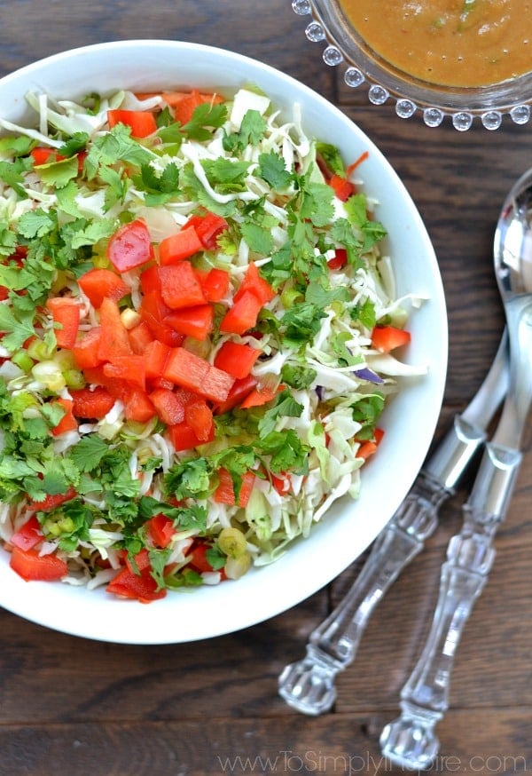 A close up of a bowl of lettuce with diced red peppers on top