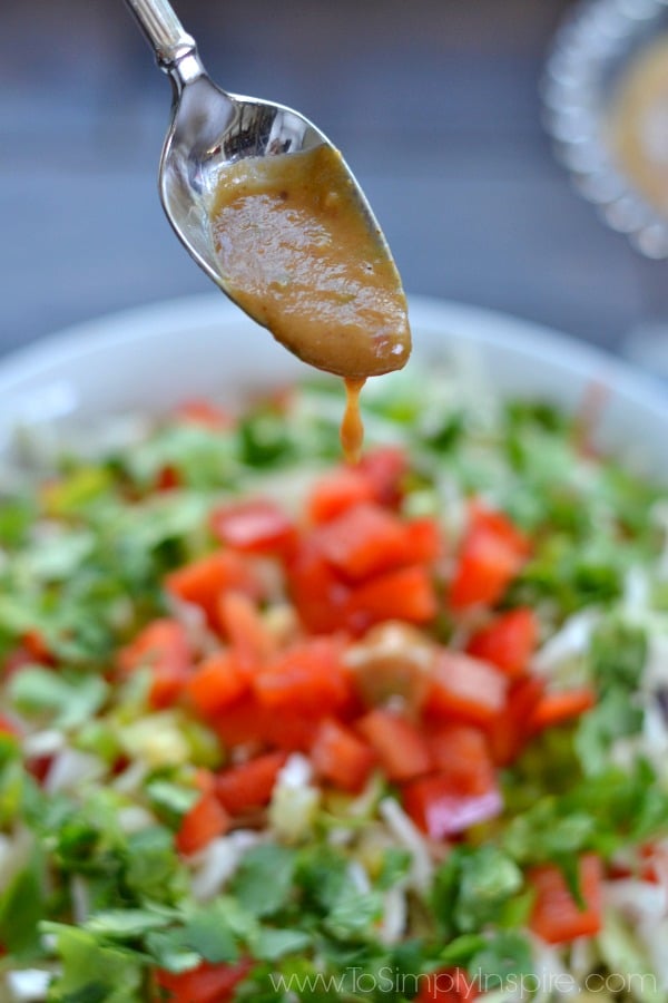 a spoon drizzling dressing over a salad
