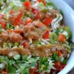 A bowl of Thai crunch salad with a peanut dressing on top.