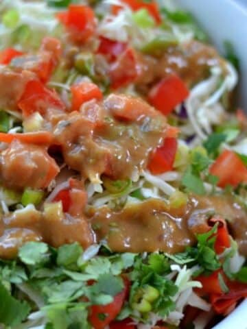 A bowl of Thai crunch salad with a peanut dressing on top.